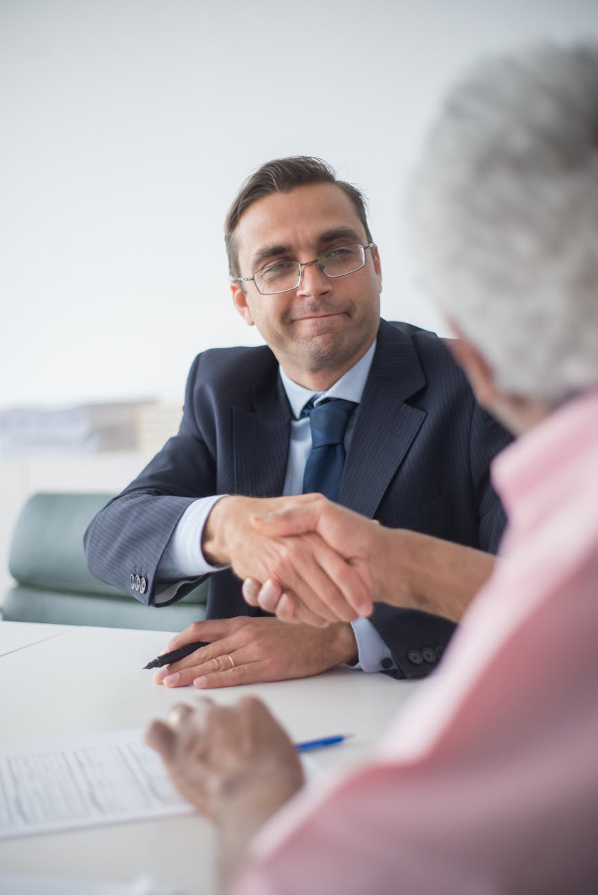 Two businessmen shaking hands in an office setting, symbolizing a successful business deal.